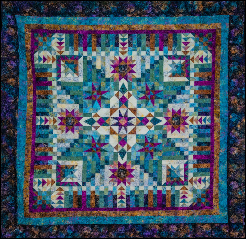 This photo shows Quilters Unlimited's Opportunity Quilt for 2025. It was constructed and quilted by Wendy Adams and bound by Janet Taylor. The pattern is "Arabella" by Wing and a Prayer Designs (permission granted). Photo by Bob O'Lary.
